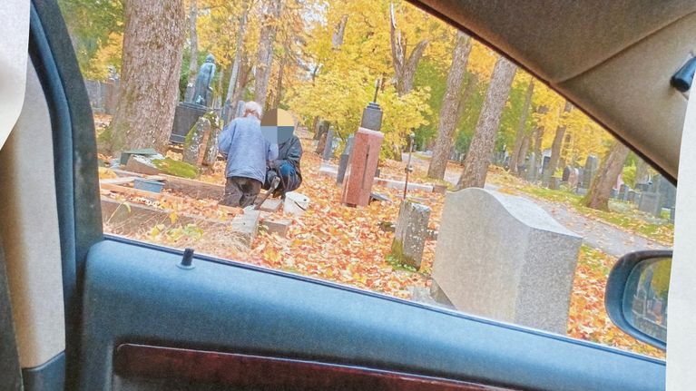 Hautausmaalla hautausmaan työntekijä juttelee haudassa seisovaa henkilö