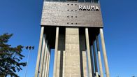 Betonisen korkean vesitornirakennuksen yläosassa lukee Rauma. Taustalla kirkkaansininen taivas. 
