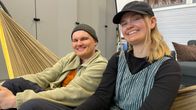 Kaksi opiskelijaa istuu luokkahuoneessa olevassa riippukeinussa ja katsoo kameraan iloisin ilmein.
