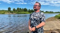Mies nauttii kalastuksesta joen rannalla aurinkoisena päivänä.