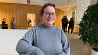 En kvinna i grå klänning som står i en aula.