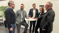 Seinäjoen kaupungin edustajat seisovat keskustelemassa pöydän äärellä.