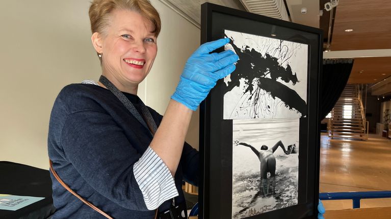 Nainen pitää käsissään mustavalkoisissa kehyksissä olevaa kuvakollaasia, jossa alaston ihminen pyllistää kameraan päin.