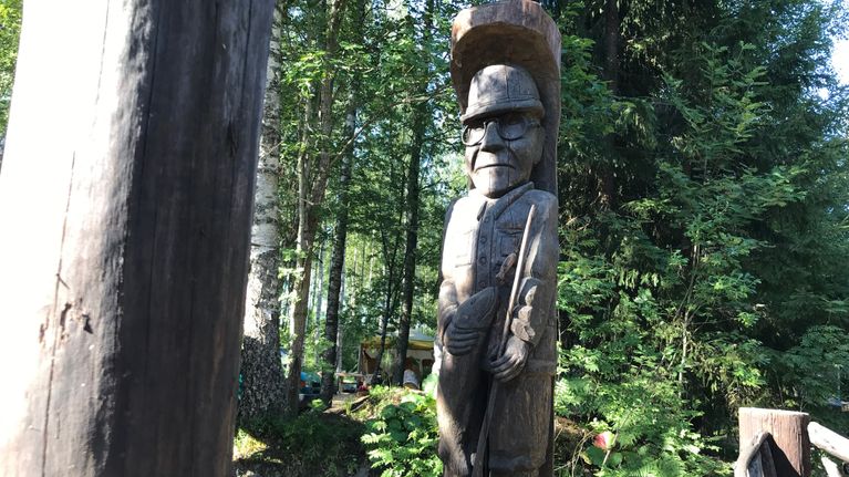 Seppo Laatusen puuveistos, joka esittää Urho Kekkosta onki ja kala kädessä.