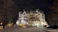 Tämä on talvinen yökuva vaikuttavasta suuresta jugendlinnasta, joka on valaistu ulkoa. Rakennusta ympäröi hiljainen luminen maisema.