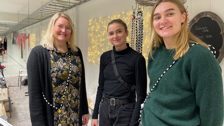 Kuvassa Kädentaitajien lahjapajan järjestäjä Minna Laatikainen seisoo tyttäriensä Emilia ja Linnea Laatikaisen kanssa myyntipöydän vierellä.  