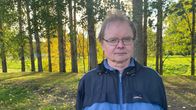 Mies katsoo kameraan, taustalla ruskametsää.