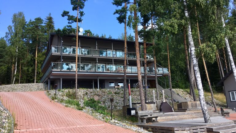 en av fastigheterna som ägs av airiston helmi. Stor byggnad med många glasfönster och en stengång i röd sten.