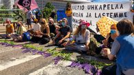 Personer demonstrerar med att sitta på bilvägen.