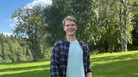 Näyttelijä Lauri Qvick katsoo hymyillen kameraan. Taustalla on vehreä puisto.