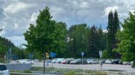 Parkkialue pilvisenä päivänä Lahdessa. Autoja parkkipaikalla, taustalla puita. 