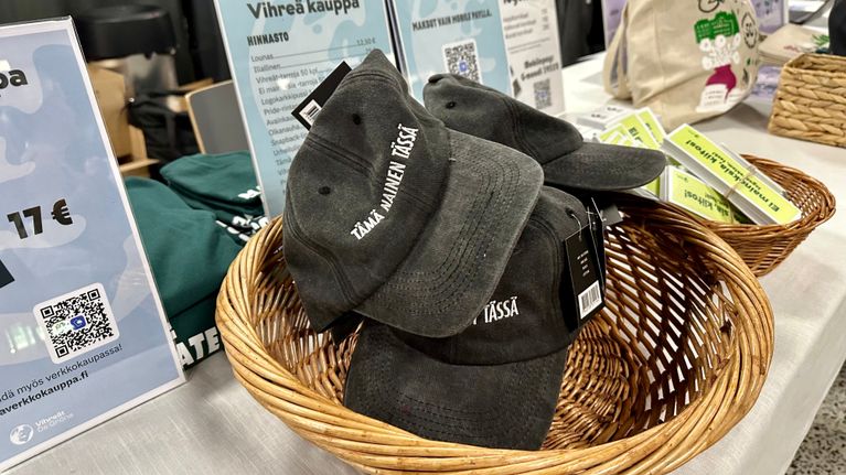 Vihreiden puoluekokouksessa myytiin lippalakkeja tekstillä "tämä nainen tässä". 