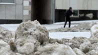 Mies lapio lunta kuvattuna kinoksen takaa.