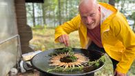 Keittiömestari Sauli Kemppainen maustaa katajan oksalla paistettuja muikkuja ulkopannulla.