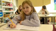 nelosluokkalainen Venla Yli-Kankahila istuu pulpetissaan ja katsoo kameraa kohti.