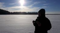 Mies juo kuumaa mehua järven jäällä kovassa pakkasessa.