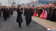 Kim Jong-Un ja hänen tyttärensä Kim Ju Ae kävelee kadulla, taustalla hurraavaa väkijoukkoa.