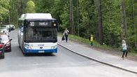 A number 10 bus to Tahmela, in Tampere, driving down a hill with woods on the side of the road.
