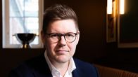 Antti Lindtman nojaa pöytään toisella kädellään katsoen kameraan.