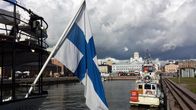 En finsk flagga syns i förgrunden. I bakgrunden Helsingfors.