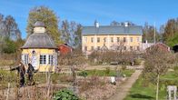 En trädgård med två gula byggnader.