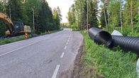 Grävmaskin och vägtrummor vid en bro på sommaren.