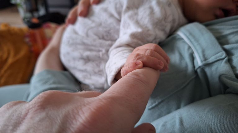 Vastasyntynyt vauva pitää kiinni miehen sormesta.