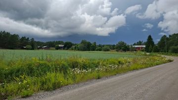 Synkkiä pilviä maalaismaiseman yllä. 
