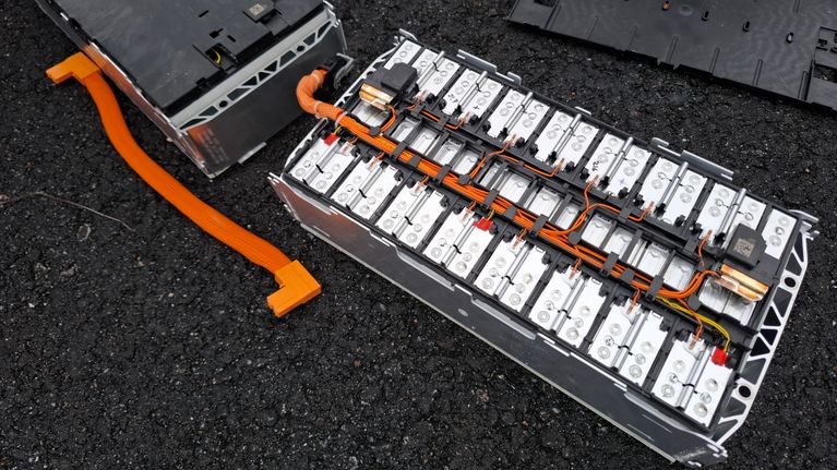 Två isärtagna batteripaket med synliga celler och kopplingar ligger på en mörk yta.