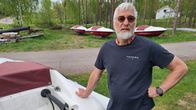 Man med grått hår och skägg vid motorbåtar utan utombordsmotor.