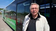 Ismo Parviainen, en man med glasögon blå pikéskjorta och ljus jacka, står framför en parkerad buss.