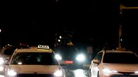 Taxis driving at night, with the lights on.