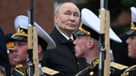 Vladimir Putin står och ser på när soldater marscherar förbi.