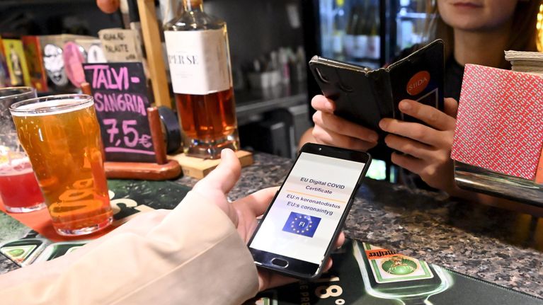 Tarjoilija tarkistaa asiakkaan koronapassia One Pint Pubin baaritiskillä Ruoholahdessa, Helsingissä.