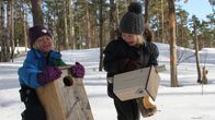 Lapset kantamassa linnunpönttöjä