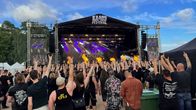 Festivaaliyleisö näyttää hevimerkkiä lavalle, jossa esiintyy bändi.