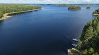 Järvi, saaria, metsiä ja oikealla kaksi venettä.