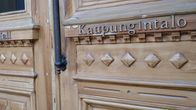 Jyväskylän kaupungintalon puinen pääovi lähikuvassa. Koristeellisessa puuovessa lukee metallisin kirjaimin suomeksi Kaupungintalo, englanniksi City Hall.