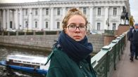 Tasja Kondratjeva nojaa sillankaiteeseen, taustalla turistivene palatsi pylväineen.