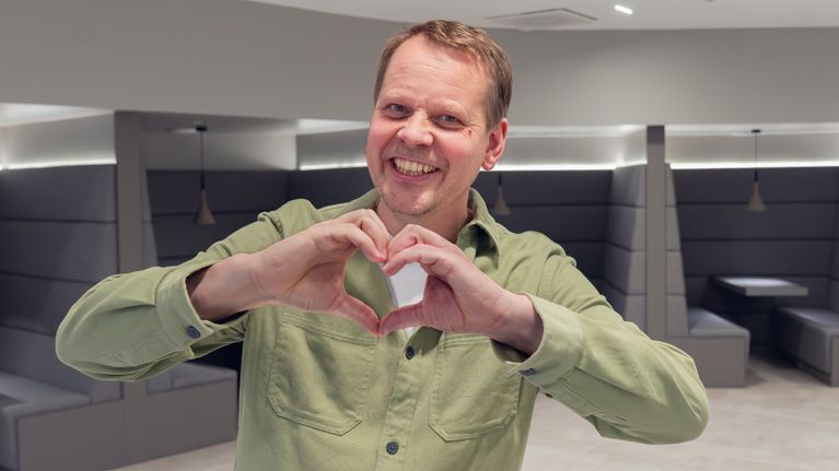 Ola Rosling tekee sormillaan sydänkuvion ja hymyilee kameralle.