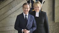 Sveriges statsminister Ulf Kristersson i kostym och hans hustru Birgitta Ed i prästskrud.