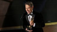 Sean Baker hymeilee ja esittelee Oscar-patsasta lavalla puhuen mikrofoniin.