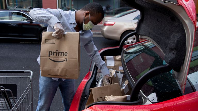 Amazonin kuljettaja lastaa ruokatoimituksia autoon Silver Springsissä, Marylandissä, 7.4.2020.