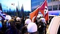 Melakkapoliisit poistavat hakaristilippuja marssijoilta.