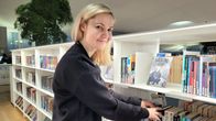 En kvinna står vid en bokhylla och ordnar med böcker.