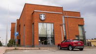 Kemijärven kaupungintalo kuvattuna sivusta. Edessä punainen auto parkissa.