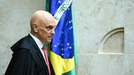 Tuomari Alexandre de Moraes seisoo oikeussalissa Brasilian lipun edessä.