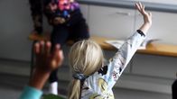 Koululaiset viittaavaat luokkahuoneessa.
