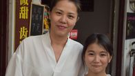 Zhou ser rakt in i kameran och ler medan hon håller om sin 10-åriga dotter som också ler mot kameran