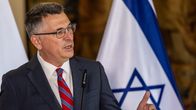 Gideon Saar puhuu puku päällä, taustalla Israelin lippu.
